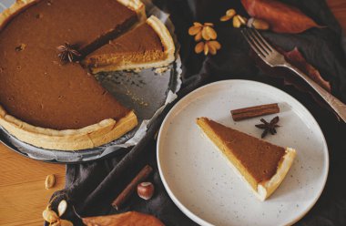 Kırsal masada, keten peçeteli, sonbahar yapraklı, anason ve tarçınlı modern tabakta balkabağı dilimi. Mutlu Şükran Günleri Ev yapımı kabak tartı tarifi.