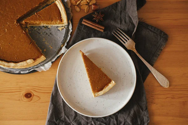 Kırsal masada, keten peçete, anason, tarçın ve çatal bıçakla modern tabakta balkabağı dilimi. Üst Manzara. Mutlu Şükran Günleri Ev yapımı kabak tartı tarifi.