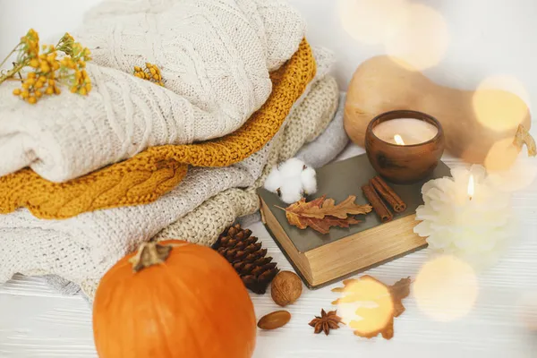舒适而缓慢的生活 舒适的毛衣 秋天的叶子 燃烧的蜡烛和在金色灯光下的古籍 房间里的白色木制背景 感恩节快乐 — 图库照片