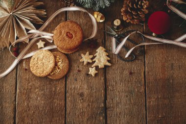 Atmosferik noel kompozisyonu, düzlük ve metin için boşluk. Noel kurabiyeleri ve sade ahşap masada süslü dekorasyonlar. Xmas sağlıklı yulaf ezmeli kurabiye ve süsler. İyi tatiller.