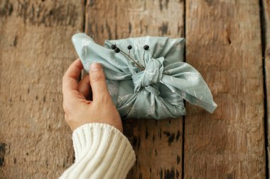 Sıfır kış tatili ve hediye boşa gitti. Furoshiki çevre dostu bir hediye. Kırsal ahşap masada dut dalıyla süslenmiş kumaşla süslenmiş şık bir Noel hediyesi. İyi tatiller.