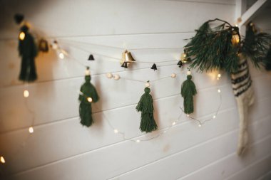 Çanları olan şık bir Noel çelengi, köknar dallı kırsal bir çorap ve ahşap duvarda noel ışıkları. Şenlikli dekore edilmiş atmosferik boho odası. Boho el yapımı dekor. Metin için boşluk
