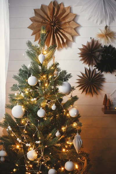 紙の星と白い壁の背景に現代的な白い泡と黄金のライトで飾られたスタイリッシュなクリスマスツリー 大気中のお祝いの北欧の部屋 クリスマス — ストック写真
