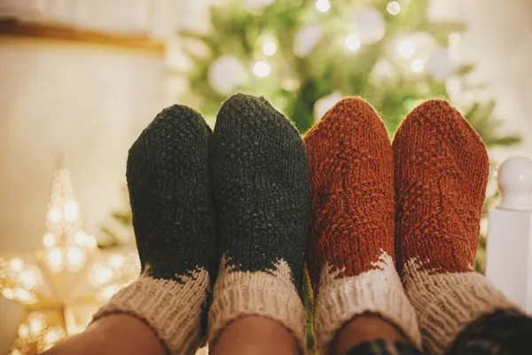 Paare Füße Gemütlichen Wollsocken Auf Dem Hintergrund Des Weihnachtsbaums Lichtern — Stockfoto