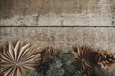 Şık noel kağıt yıldızları, köknar dalları ve kozalaklar eski ahşap arka planda sınırdır. Noel kırsalında düz bir yerde, mesaj için yer vardı. Sezonun tebrik kartı. Mutlu Noeller.!