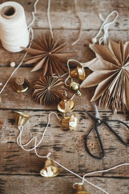 Şık Noel çanları, kağıt yıldızlar, mum, iplik ve makas kırsal ahşap arka planda. Şenlikli İskandinav çelengi yapmak, atmosferik bayram dekorasyonu. Mutlu Noeller.