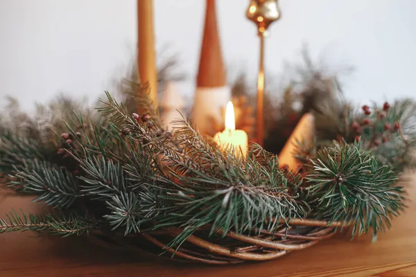 圣诞节来了圣诞花圈里燃烧着时尚的蜡烛 在喜庆的房间里 在白墙的背景下 木桌上用松果和树装饰着 大气冬季假期 — 图库照片