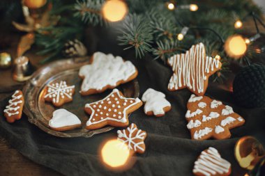 Noel kurabiyeleri, köknar dalları, peçete üzerindeki sıcak ışıklar ve kırsal ahşap masa. Huysuz atmosferik görüntü. Kış kızarıklığı. Mutlu tatiller ve mevsimler.