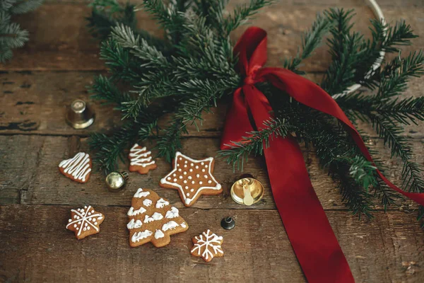 素朴な木製のテーブルの上に赤い弓でクリスマスジンジャーブレッドクッキーとスタイリッシュなクリスマスリース 季節の挨拶と幸せな休日 冬時間だ ムーディー大気画像 — ストック写真