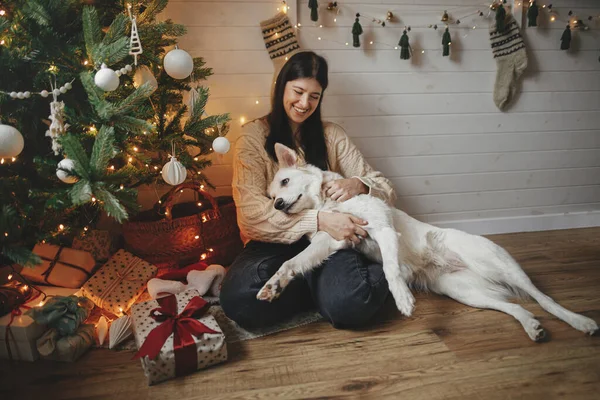 Κομψό Ευτυχισμένη Γυναίκα Αγκαλιάζει Αξιολάτρευτο Σκυλί Κάτω Από Χριστουγεννιάτικο Δέντρο — Φωτογραφία Αρχείου