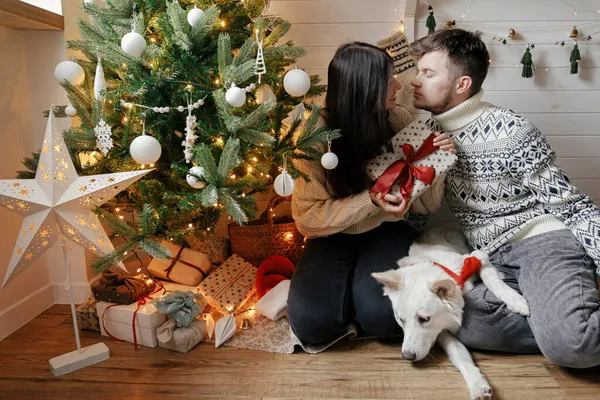 Elegante Pareja Con Lindo Perro Sosteniendo Regalo Navidad Con Lazo — Foto de Stock