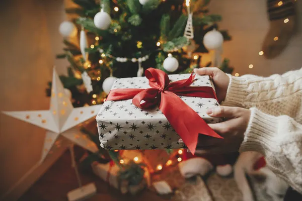Eingewickeltes Weihnachtsgeschenk Mit Roter Schleife Den Händen Kuscheligem Strickpullover Auf — Stockfoto