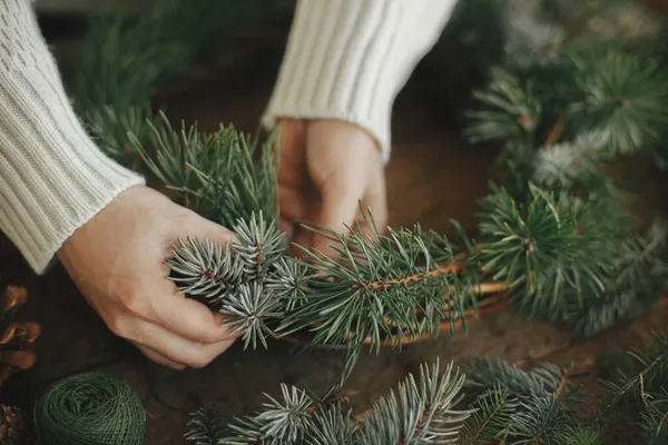 Frau Hält Tannenzweig Der Hand Und Arrangiert Adventskranz Auf Rustikalem — Stockfoto