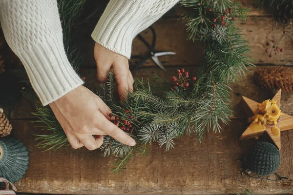 Frauenhände Halten Rote Beeren Der Hand Und Arrangieren Weihnachtskranz Auf — Stockfoto
