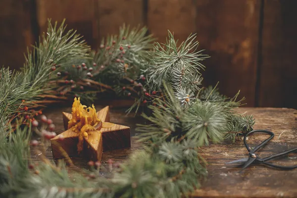 圣诞节来了别致的圣诞花环 带有云杉枝条和浆果 星形蜡烛和剪子在乡村的木制背景 圣诞快乐 节日快乐 大气喜怒无常的图像 — 图库照片