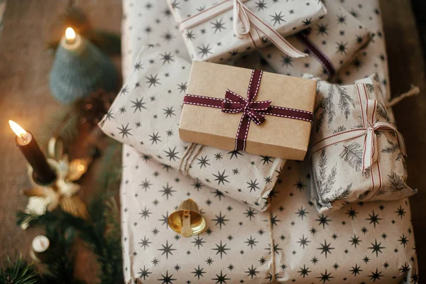 用牛皮纸 老式蜡烛 冷杉枝条和铃铛包裹着别致的圣诞礼物 时尚的丑闻鸟类的圣诞礼物 大气冬季时间 圣诞快乐 — 图库照片