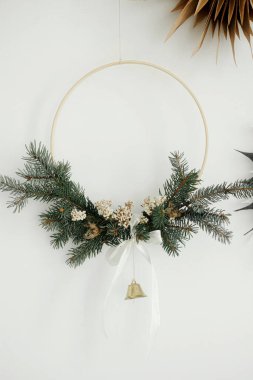 Mutlu Noeller ve mutlu Noeller! Beyaz arka planda asılı modern noel çelengi ve İsveçli kağıt yıldızlar. Atmosferik zaman. Zilli minimalist Xmas boho çelengi