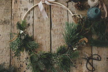 Modern noel çelengi düzdü. Kırsal ahşap arka planda şık xmas çelenkleri, dallar, bitkiler, mum, makas, iplik, kozalaklar. Huysuz bir görüntü. Mutlu Noeller.!
