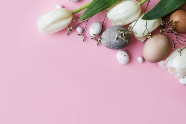 Mutlu Paskalyalar! Şık yumurtalar, pembe arka planda düz laleler. Modern doğal boyalı paskalya yumurtaları ve beyaz laleler. Tebrik kartı şablonu, paskalya arkaplanı. Metin için boşluk