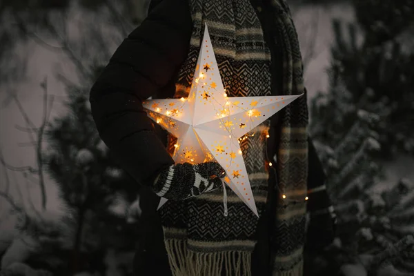 一个女人在雪地的冬日公园里抱着一颗明亮的大圣诞星 关门了 神奇的冬季时间 时髦的嬉皮士女性与闪亮的圣诞明星 圣诞快乐 圣诞节的奇迹 — 图库照片