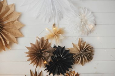 Beyaz ahşap duvarda ışıkları olan şık Noel yıldızları. Modern İskandinav şenliği dekoru. Basit İsveçli kağıt yıldızlar. Kış tatili hazırlıkları. Mutlu Noeller.!