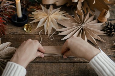 Şık Noel yıldızları yapmak. El yapımı İsveç yıldızlarının arka planında el işi kağıt katlama, iplik, mum, kırsal ahşap üzerinde makas. Şenlik dekoru yapma süreci. Tatil hazırlıkları