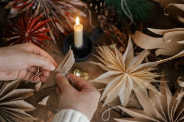 Şık Noel yıldızları yapmak. El yapımı İsveç yıldızlarının arka planında katlanmış el işi kağıt, iplik, mum, kırsal kesimde makas. Festivalsel dekor oluşturma süreci.