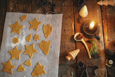 Noel yıldızında zencefilli çörekler ve kırsal arka planda kabartma kağıdında ağaç şekilleri. Düz yatıyordu. Atmosferik Moody görüntüsü. Kırsal masada geleneksel zencefilli kurabiye yapıyorum.