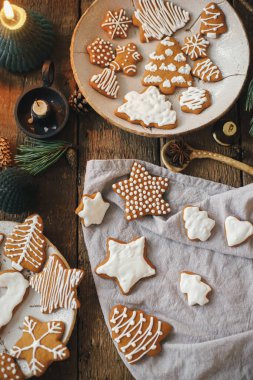 Kırsal masada süslenmiş zencefilli kurabiyeler peçete, mum, dekorasyon ve baharatlarla. Düz yatıyordu. Atmosferik karamsar görüntü. Havalı Noel kurabiyeleri yapmak için. Mutlu Noeller.!