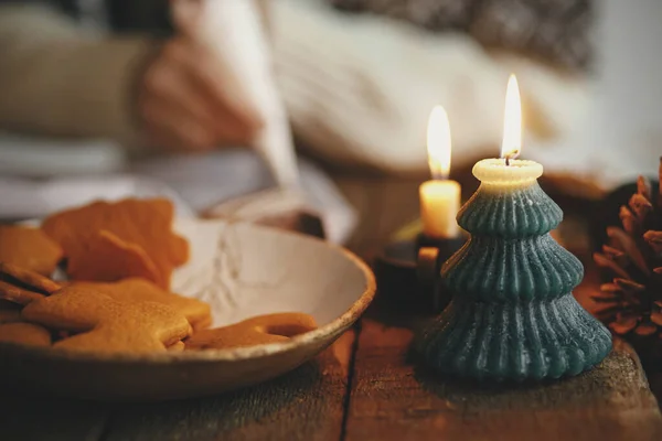 新鲜烘焙的圣诞姜饼和时尚的蜡烛背景下的女人装饰饼干在乡村的桌子上 喜怒无常的形象做传统的圣诞姜饼饼干 — 图库照片