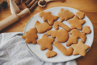 Modern tabakta nefis fırınlanmış zencefilli kurabiyeler peçeteli, oklavalı, baharatlı ahşap masa. Noel kurabiyelerini kapatıyoruz. Tatil hazırlığı, xmas aşçılığı. Bisküvi tarifi