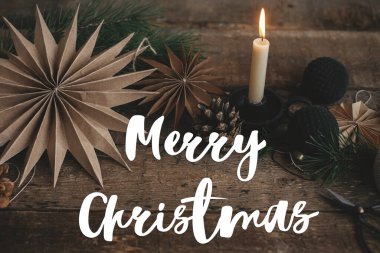 Şık Noel kâğıdı yıldızları, mum, süsler ve kır ağacında çam kozalağı üzerine Mutlu Noeller metni. Mevsimlik tebrik kartı. El yazısı işareti