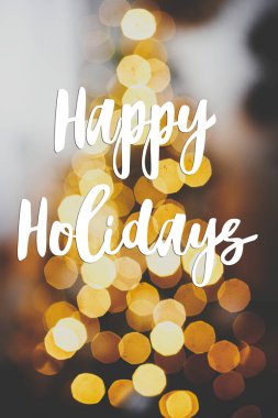 Altın Noel ağacı ışıklarıyla ilgili iyi tatiller mesajı. Akşam şenlik odasında. Atmosferik Noel arifesi. Sezonun tebrik kartı. El yazısıyla yazılmış işaret. Mutlu Noeller.!