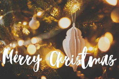 Mutlu Noeller tebrik kartı. Modern noel ağacı, beyaz takı, altın noel ışıkları hakkındaki mutlu noel metni bokeh. İyi tatiller! El yazısı işareti