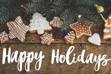 Mutlu Noel mesajları zencefilli kurabiye, köknar dalları, sade ahşap yatakta sıcak ışıklar. Sezonun tebrik kartı. El yazısıyla yazılmış işaret. Mutlu Noeller.!