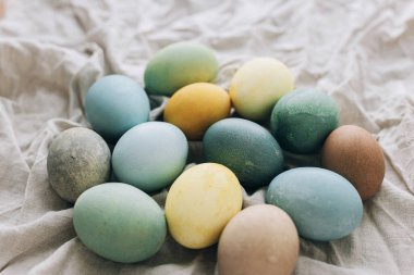 Paskalya yumurtaları kırsal çarşaf peçetesinde. Mutlu Paskalyalar! Doğal boyalı pastel renkli yumurta kompozisyonu. Kırsal yaşam, üst görünüm