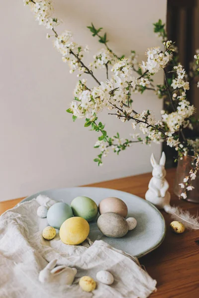 复活节快乐 复活节彩蛋盘中的兔子雕像 亚麻布餐巾 樱花在乡村餐桌上 天然染色彩蛋和春花 乡村静谧的生活 — 图库照片