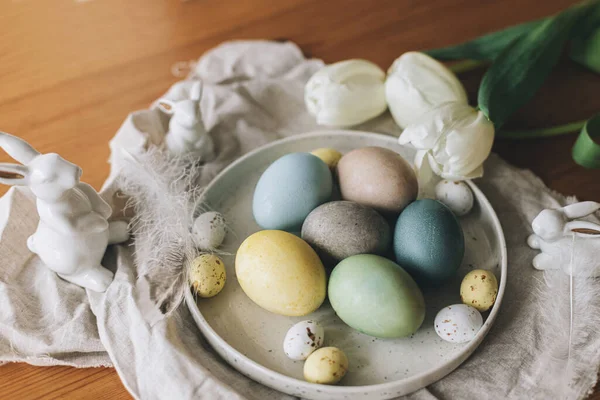 复活节彩蛋放在盘子里 上面有兔子的雕像 亚麻布餐巾 乡村餐桌上有郁金香 复活节快乐 天然染色彩蛋和春花 乡村静谧的生活 — 图库照片