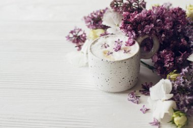 Leylak yapraklı nefis kahve, kır beyazı ahşap arka planda gül ve leylak dalı. Merhaba bahar. Mesaj için yer var. Anneler Günün kutlu olsun. Günaydın natürmort