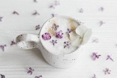 Beyaz ahşap arka planda leylak yapraklı lezzetli kahve. Anneler Günün kutlu olsun. Günaydın, hoş geldin baharı. Güzel çiçekler şık bir fincan kahvede durgun bir hayat.