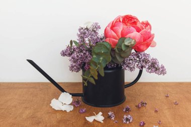 Kırsal arka planda modern çiçeklerin hayat düzenlemesi. Güzel şakayık, leylak çiçekleri ve okaliptüs, şık metal sulama kabında. Anneler Günün kutlu olsun. Merhaba bahar.