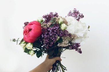 Modern düğün buketi. Beyaz arka planda kadın eli şeklinde bir buket. Anneler Günün kutlu olsun ya da Sevgililer Günü. Güzel bir şakayık, leylak, gül, ortanca çiçeği ve okaliptüs..