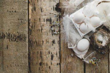 Paskalya kırsalı düzlüğü, yazı için boşluk. Tepside doğal yumurtalar, tüyler, söğüt dalları, eski ahşap masaya yuva. Paskalya kırsalındaki şık yaşam. Basit bir estetik. Mutlu Paskalyalar