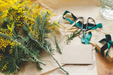 Mimoza buketi, hediye kutusu ve tahta arka planda tebrik kartı. Mutlu kadınlar günü ve mutlu anneler günü. Tebrik kartı şablonu metin için boşluk ile birlikte. 8 Mart kavramı