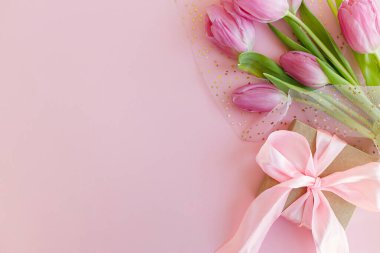 Pembe laleler ve pembe arka planda duran hediye kutusu. Tebrik kartı şablonu metin için boşluk ile birlikte. Mutlu kadınlar günü. 8 Mart. Anneler Günün kutlu olsun.