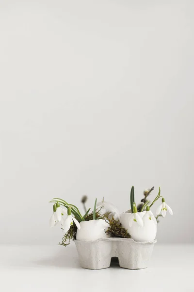 イースター素朴な静物画 白い木製のテーブルの上に開花の雪滴と苔を持つイースターエッグシェル テーブルの上にシンプルなスタイリッシュなお祝いの装飾 ハッピーイースター テキストのスペース — ストック写真