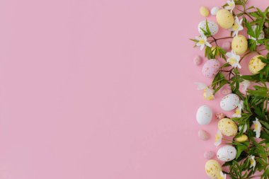 Mutlu Paskalyalar! Renkli Paskalya çikolatası yumurtaları ve bahar çiçekleri pembe arka planda. Havalı paskalya yatağı. Tebrik kartı ya da afiş