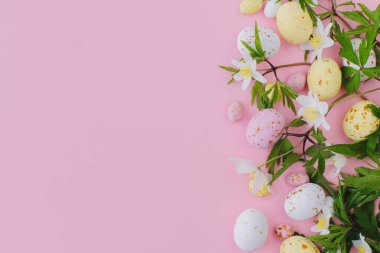Renkli Paskalya çikolatası yumurtaları ve bahar çiçekleri pembe arka planda. Mutlu Paskalyalar! Havalı paskalya yatağı. Tebrik kartı ya da afiş