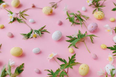 Mutlu Paskalyalar! Renkli Paskalya çikolatası yumurtaları ve pembe arka planda bahar çiçekleri. Paskalya planınız çok şık. Tebrik kartı ya da afiş. Şeker ve çiçek kompozisyonu
