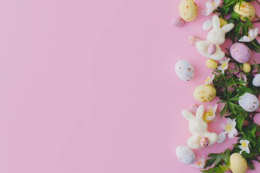 Mutlu Paskalyalar! Renkli Paskalya çikolatası yumurtaları, tavşanlar ve bahar çiçekleri pembe arka planda yatıyordu. Paskalya planınız çok şık. Tebrik kartı veya pankart şablonu